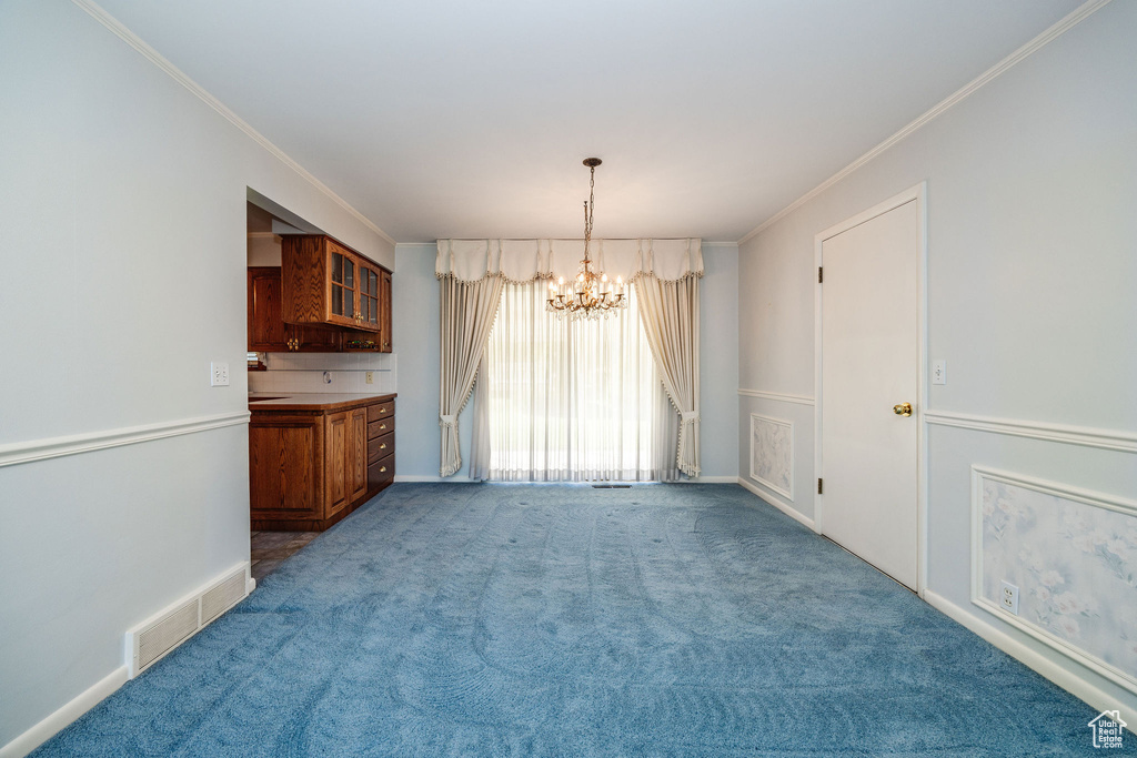 Unfurnished dining area featuring a chandelier, light colored carpet, and crown molding