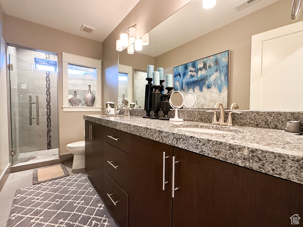 Bathroom featuring a shower with shower door, vanity, and toilet