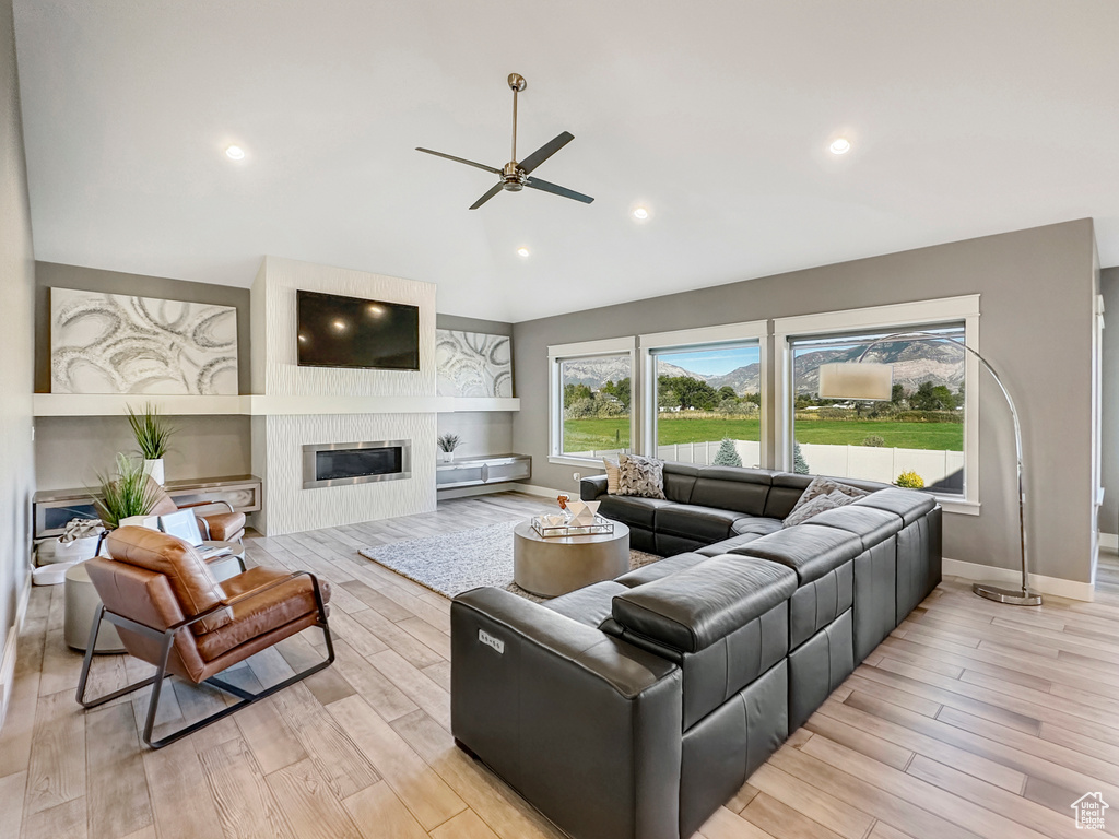 Living room with a large fireplace, light hardwood / wood-style floors, and ceiling fan