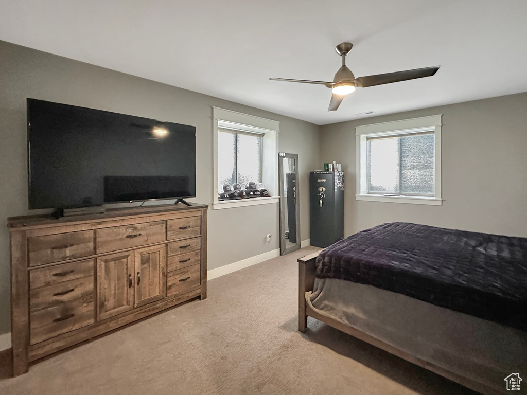 Bedroom with ceiling fan, light colored carpet, and multiple windows