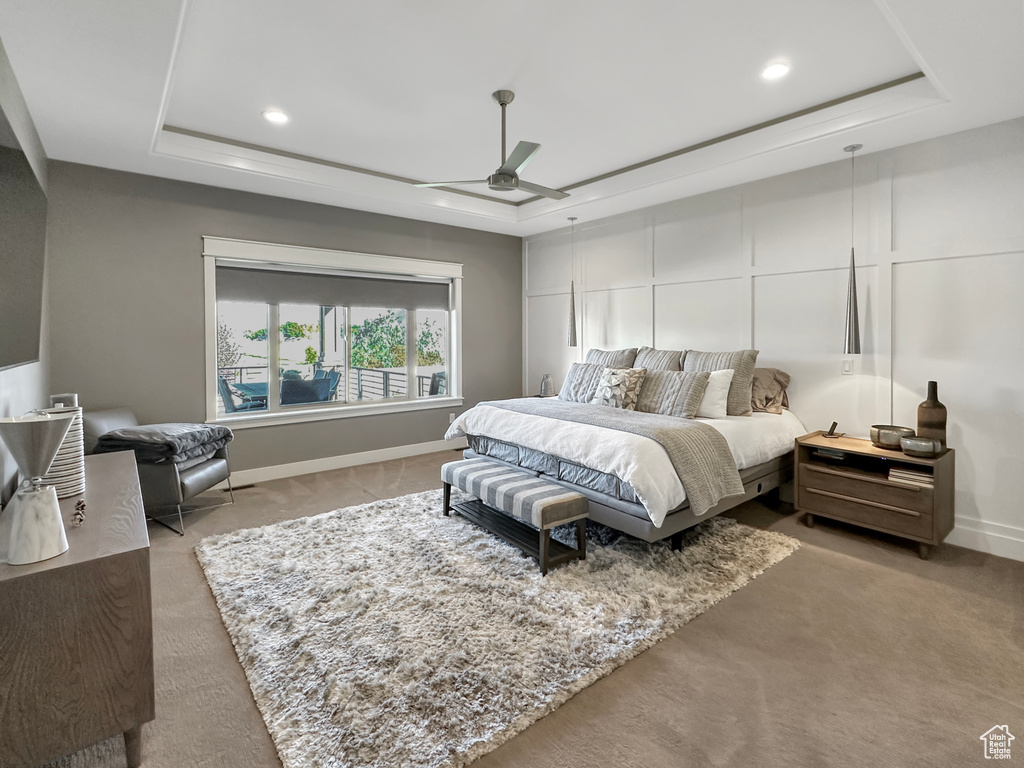 Carpeted bedroom with ceiling fan and a raised ceiling