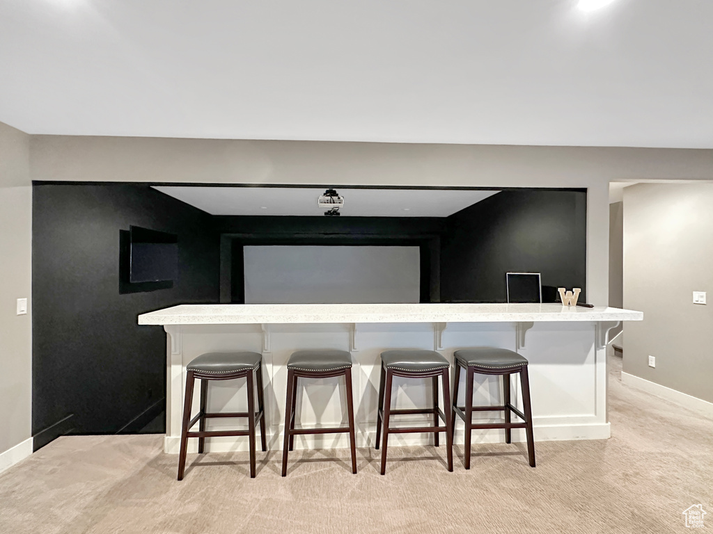 Kitchen featuring light colored carpet and a breakfast bar area