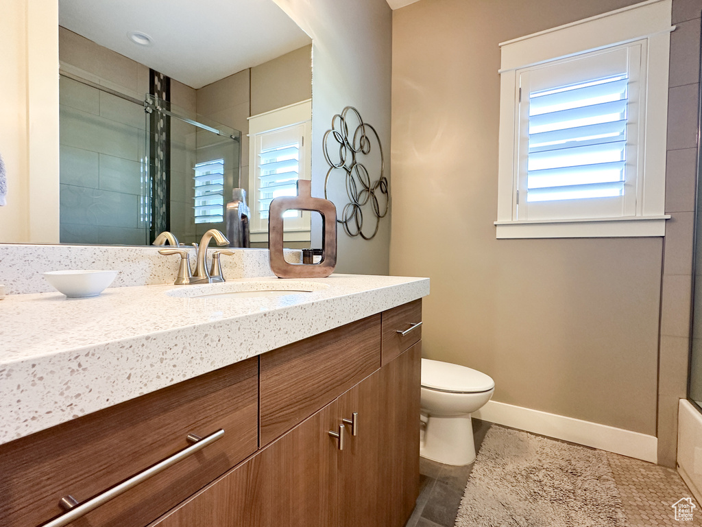 Bathroom featuring walk in shower, vanity, toilet, and tile patterned floors