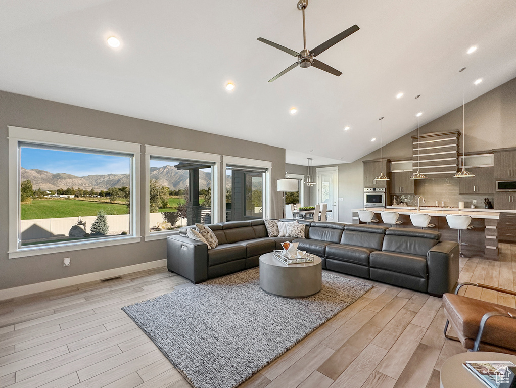 Living room with ceiling fan, a mountain view, light hardwood / wood-style flooring, and high vaulted ceiling