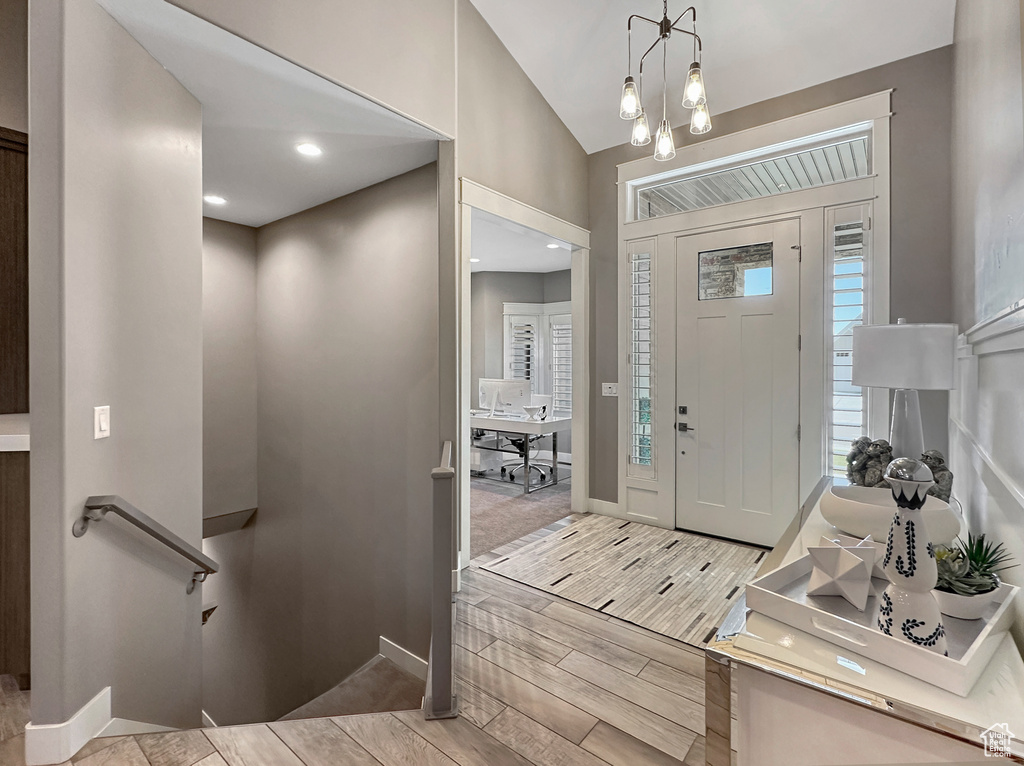 Entryway featuring light hardwood / wood-style floors, vaulted ceiling, and a notable chandelier