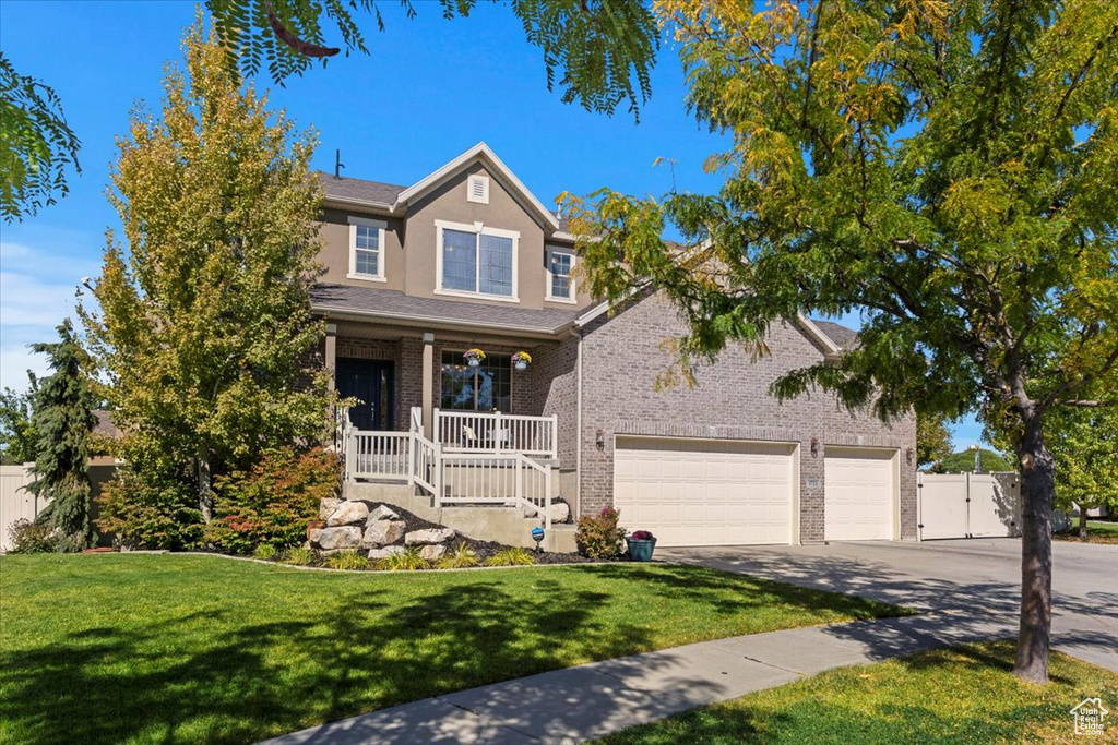 View of front of property featuring a garage, a front yard, and covered porch