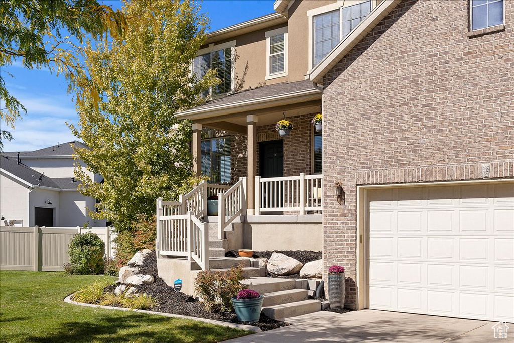 View of front of house with a front lawn, a garage, and covered porch