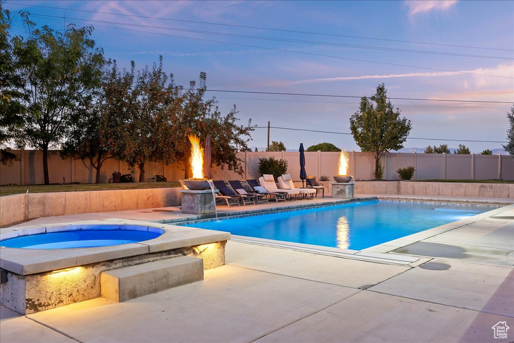 Pool at dusk with a patio and an in ground hot tub