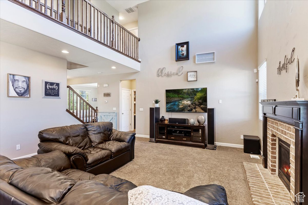 Living room with carpet floors, a towering ceiling, and a brick fireplace