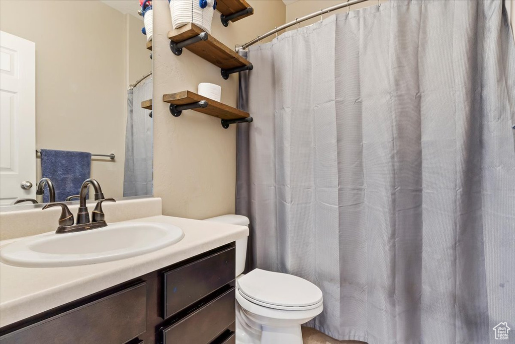 Bathroom featuring curtained shower, vanity, and toilet