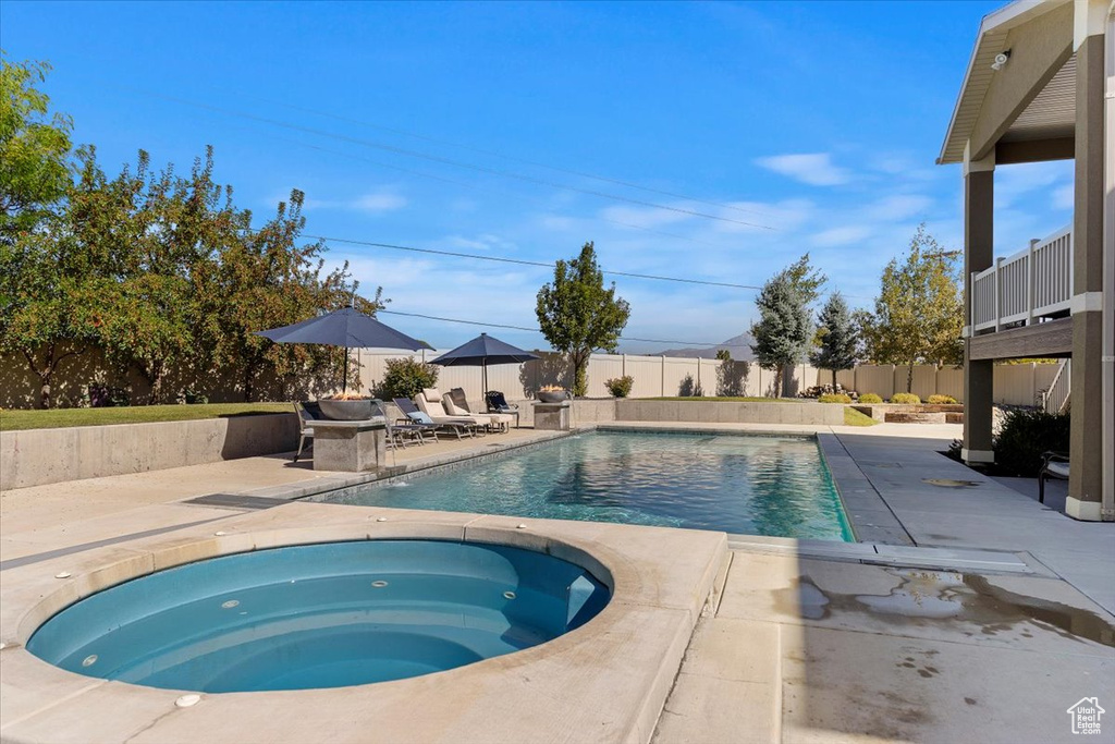 View of swimming pool with an in ground hot tub and a patio area