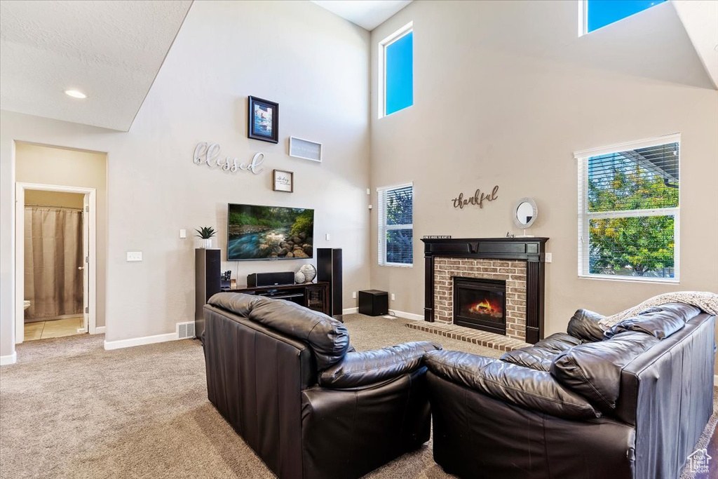 Carpeted living room with a fireplace and high vaulted ceiling