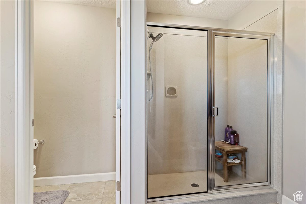 Bathroom with a textured ceiling, tile patterned flooring, and a shower with door