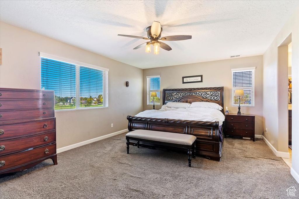 Carpeted bedroom featuring a textured ceiling and ceiling fan