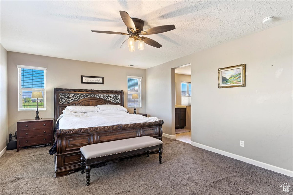 Bedroom featuring connected bathroom, ceiling fan, light colored carpet, and a textured ceiling