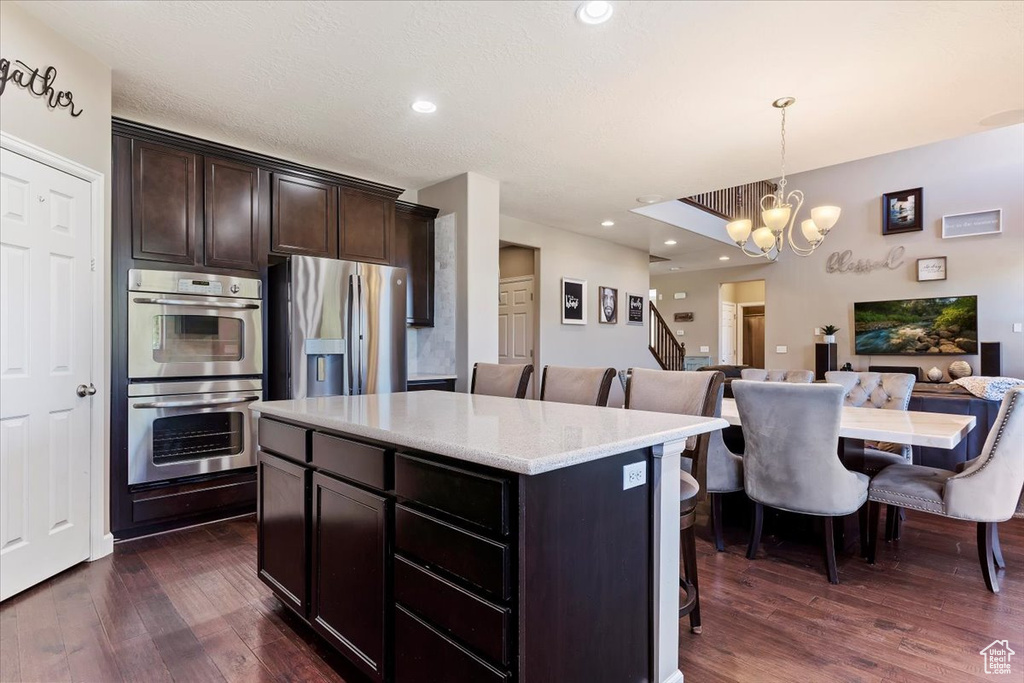 Kitchen with dark hardwood / wood-style floors, hanging light fixtures, a center island, and stainless steel appliances