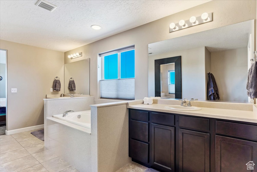 Bathroom with vanity, a bathing tub, a textured ceiling, and tile patterned floors