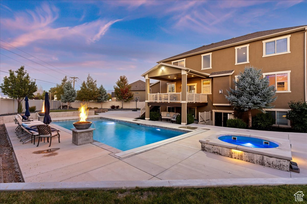 Pool at dusk with a fire pit, an in ground hot tub, and a patio area