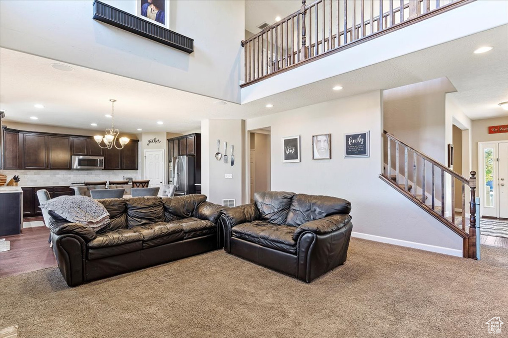 Living room with a high ceiling, carpet flooring, and a chandelier