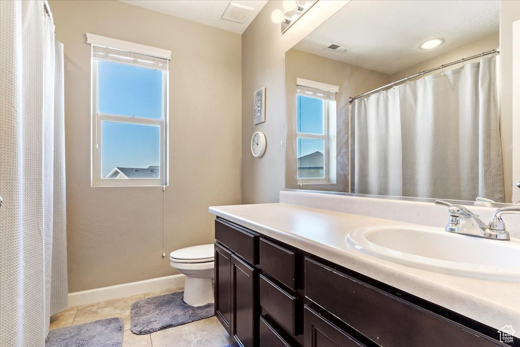 Bathroom featuring curtained shower, tile patterned flooring, vanity, and toilet