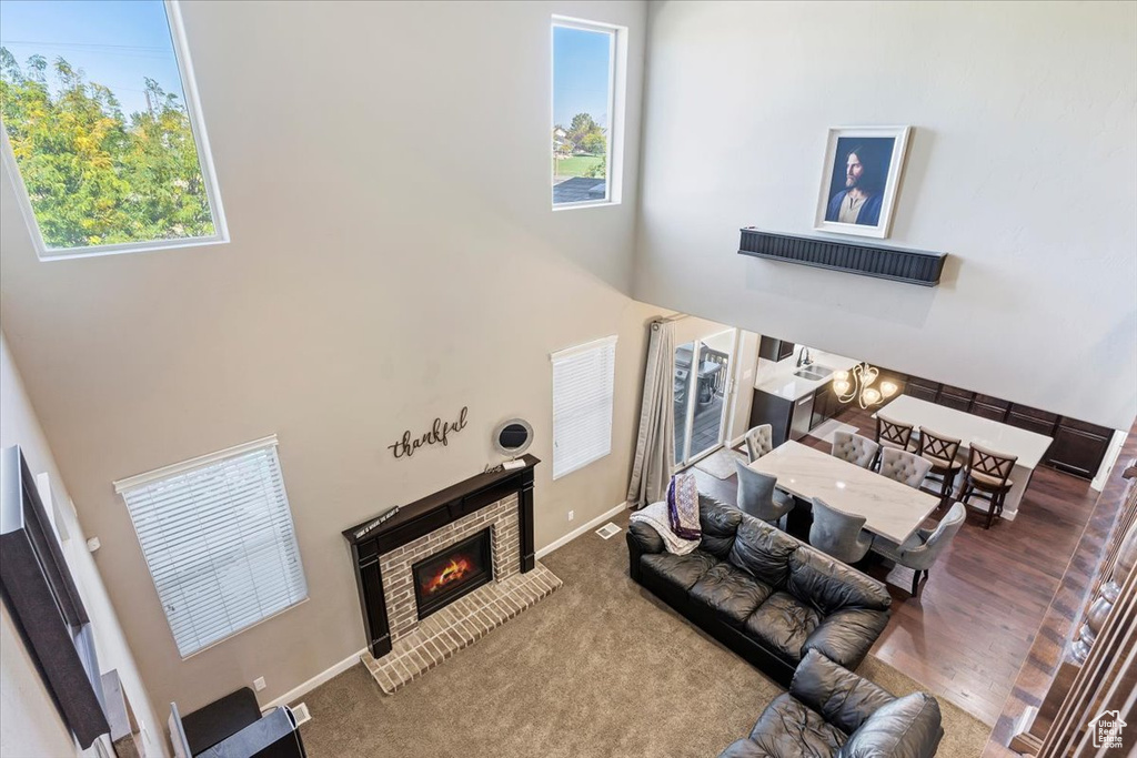 Living room featuring carpet floors, a high ceiling, and a brick fireplace