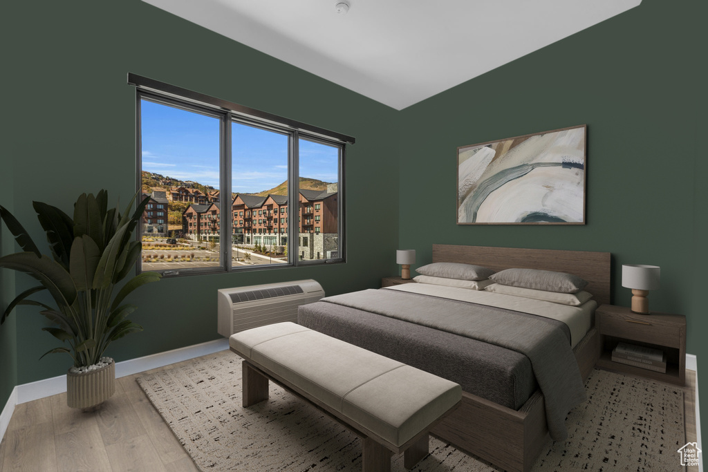 Bedroom featuring baseboards, wood finished floors, and a wall mounted air conditioner