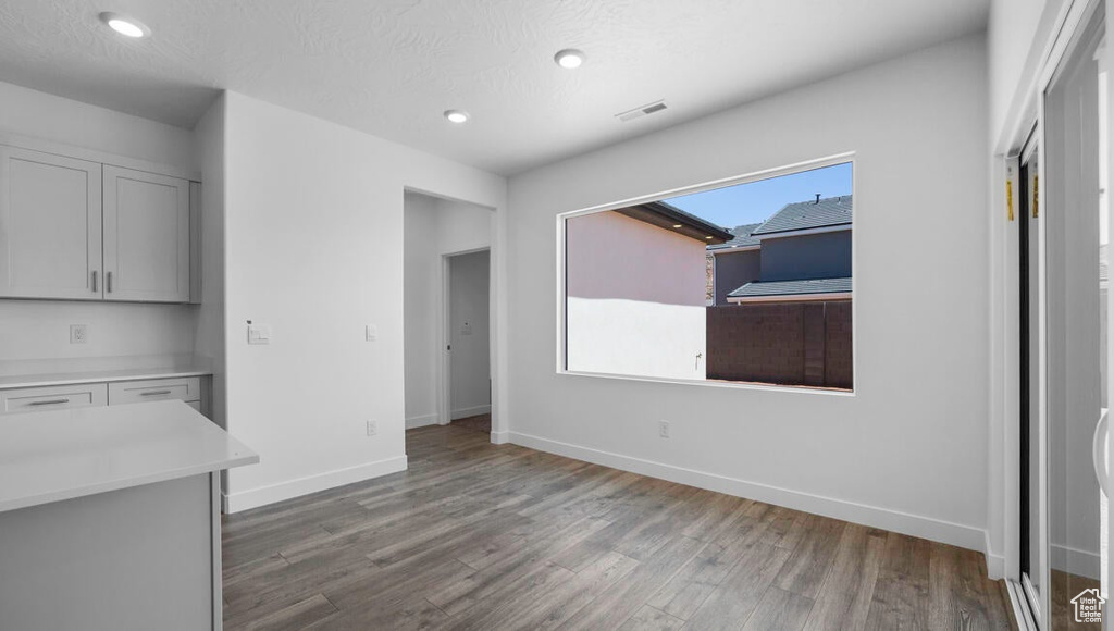 Unfurnished dining area with a textured ceiling and hardwood / wood-style flooring