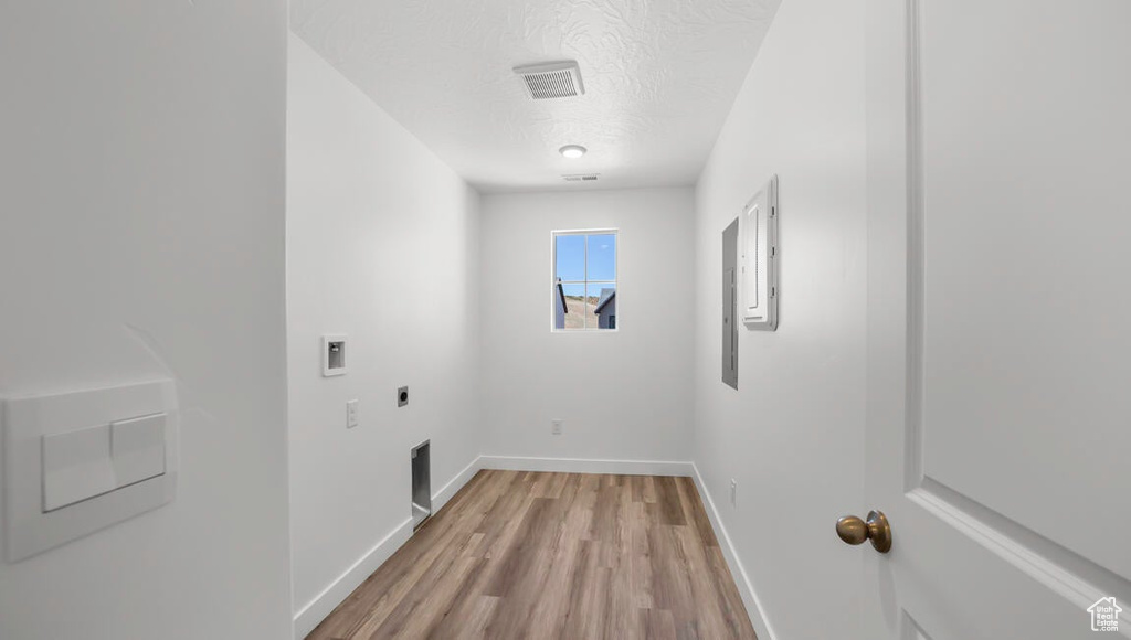 Washroom with hookup for a washing machine, a textured ceiling, electric dryer hookup, and light hardwood / wood-style flooring