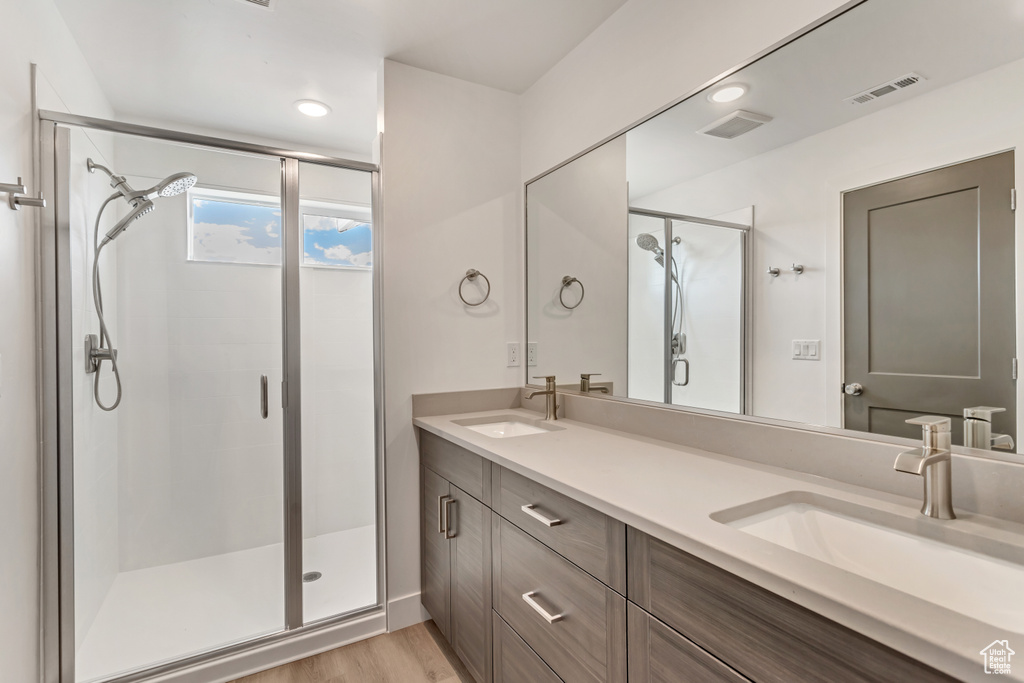 Bathroom with wood-type flooring, vanity, and a shower with shower door