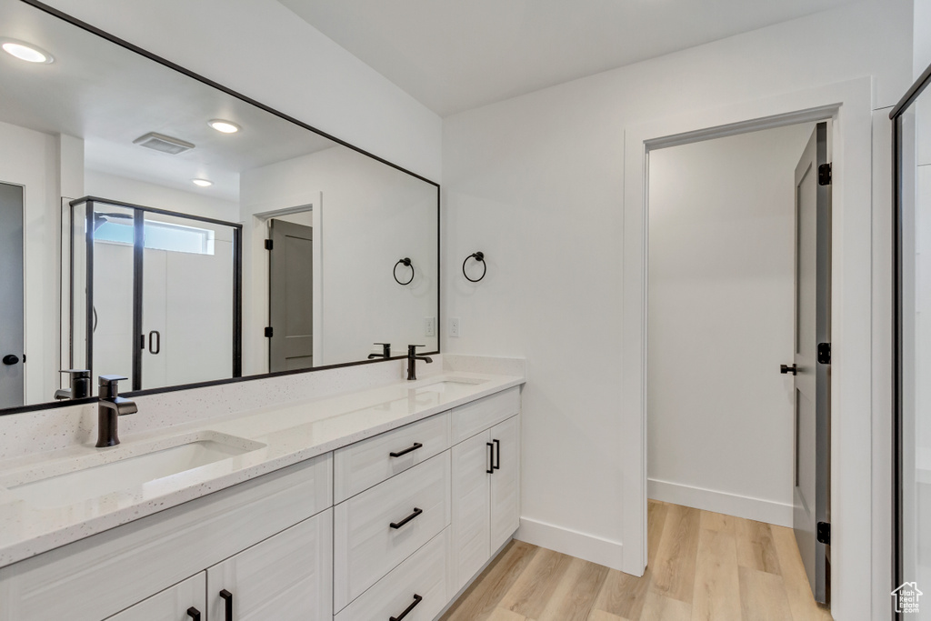 Bathroom with vanity, a shower with door, and hardwood / wood-style flooring