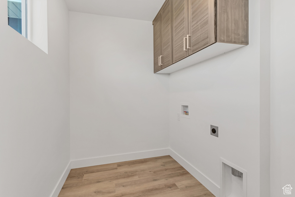 Washroom with hookup for a washing machine, cabinets, light wood-type flooring, and hookup for an electric dryer