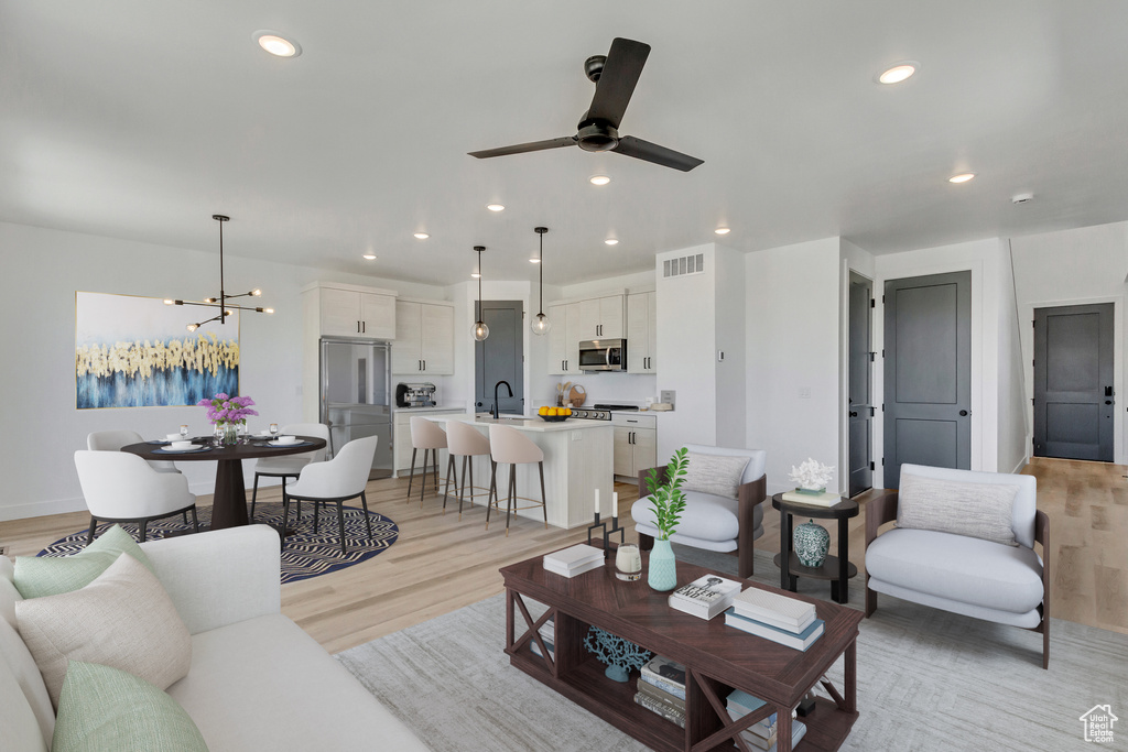 Living room with sink, ceiling fan with notable chandelier, and light hardwood / wood-style floors