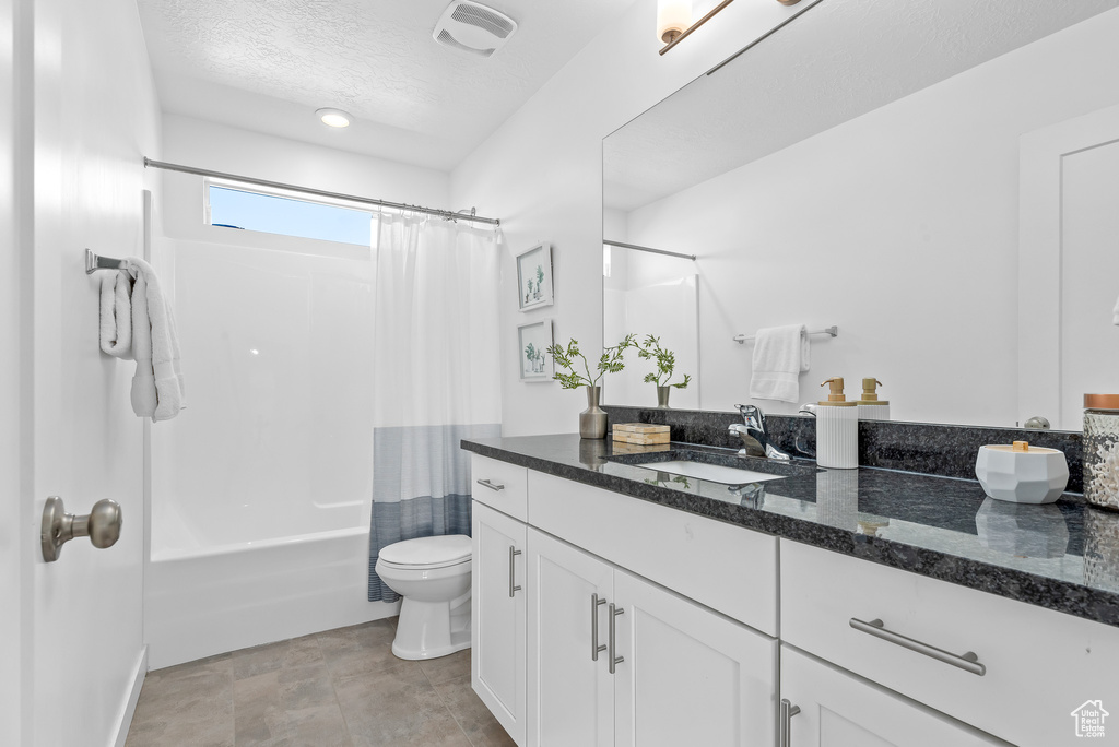 Full bathroom with vanity, toilet, a textured ceiling, and shower / tub combo with curtain