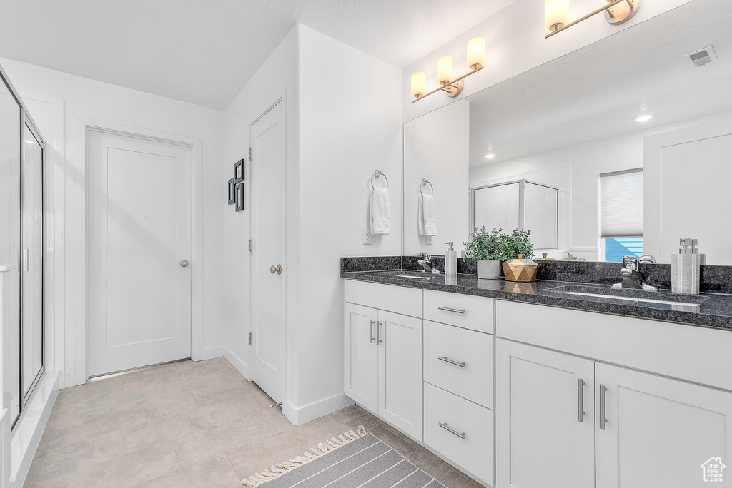 Bathroom featuring a shower with shower door and vanity