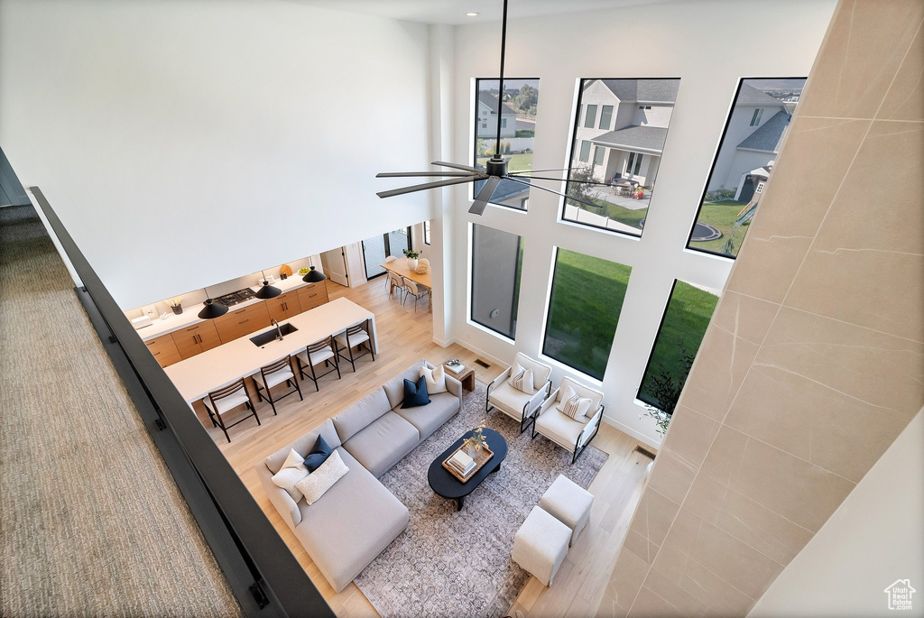 Living room featuring wood-type flooring, a high ceiling, and ceiling fan