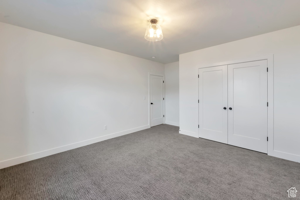 Unfurnished bedroom with dark carpet and a closet