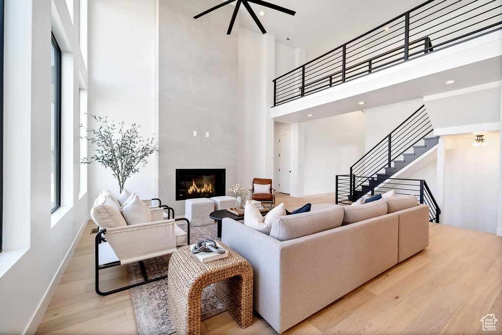 Living room featuring light wood-type flooring, a towering ceiling, and a fireplace