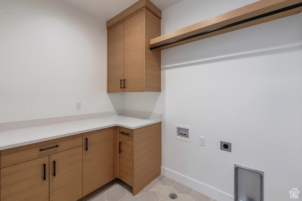 Laundry area with hookup for a washing machine, cabinets, light tile patterned floors, and electric dryer hookup