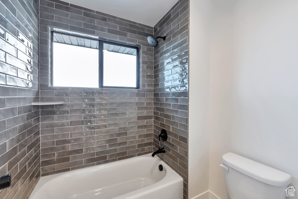 Bathroom with tiled shower / bath and toilet