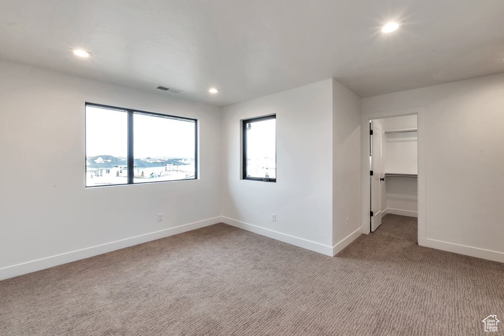 Unfurnished bedroom featuring carpet flooring, a spacious closet, and a closet