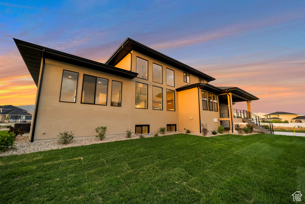 Back house at dusk featuring a yard