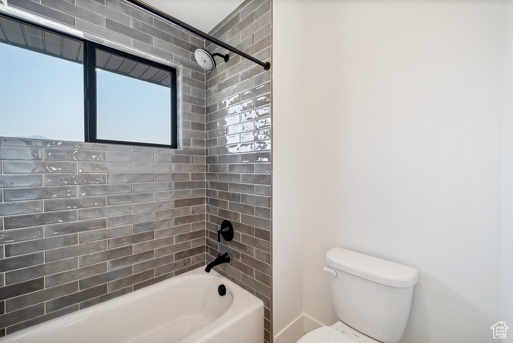 Bathroom with tiled shower / bath and toilet