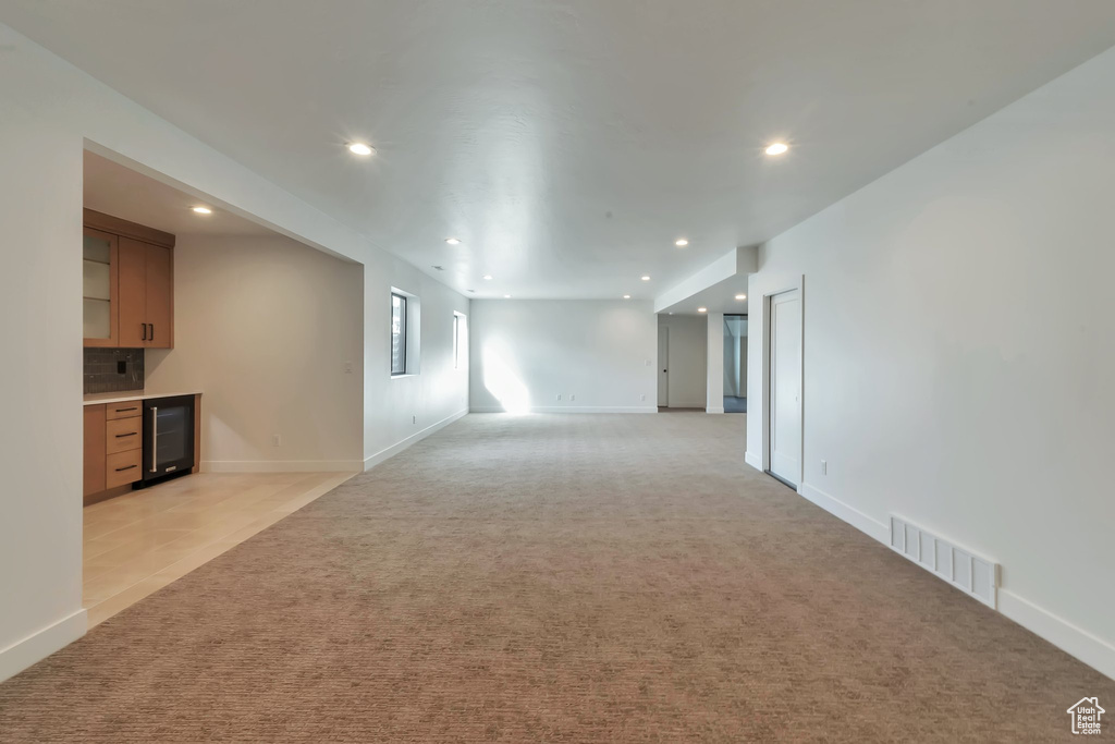 Unfurnished room featuring light colored carpet and wine cooler