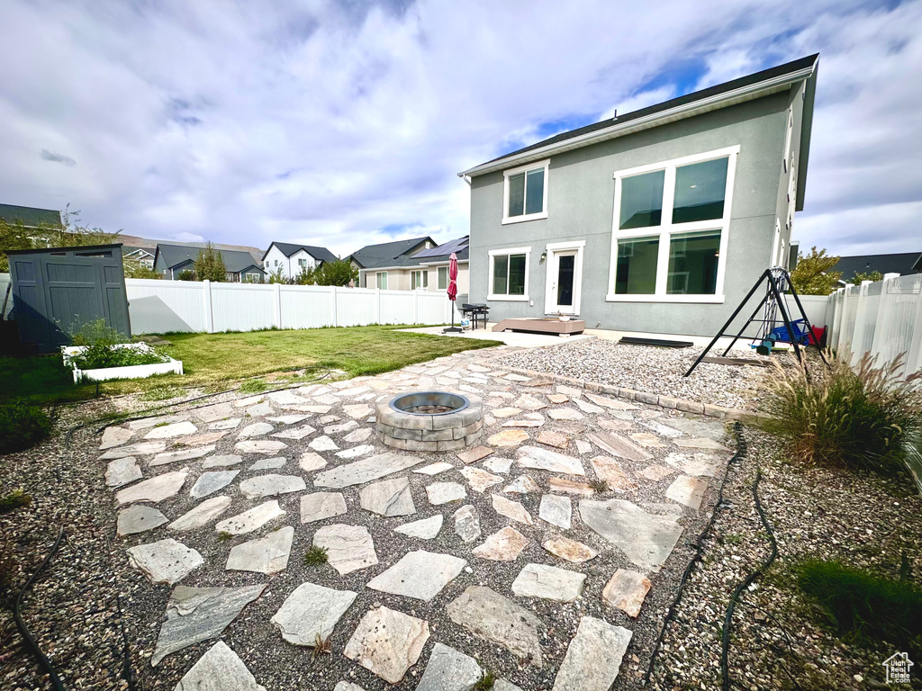 Rear view of house featuring a fire pit, a yard, and a patio