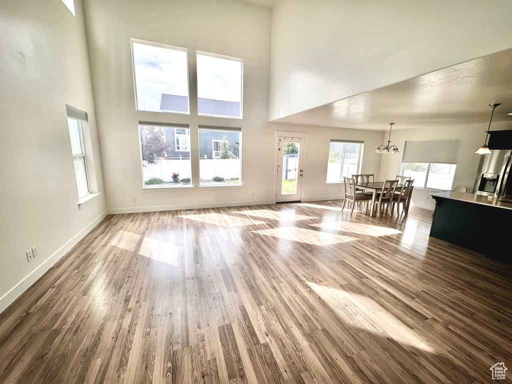 Unfurnished living room with a towering ceiling, a chandelier, and hardwood / wood-style floors