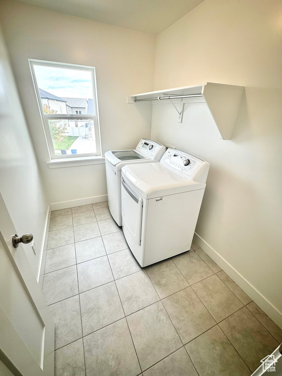 Washroom with washing machine and dryer and light tile patterned flooring