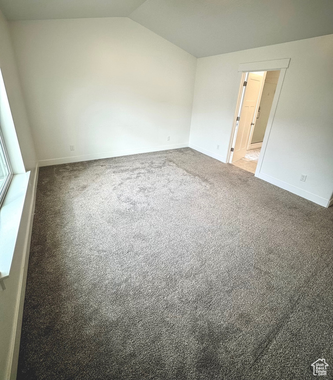 Spare room featuring carpet and lofted ceiling