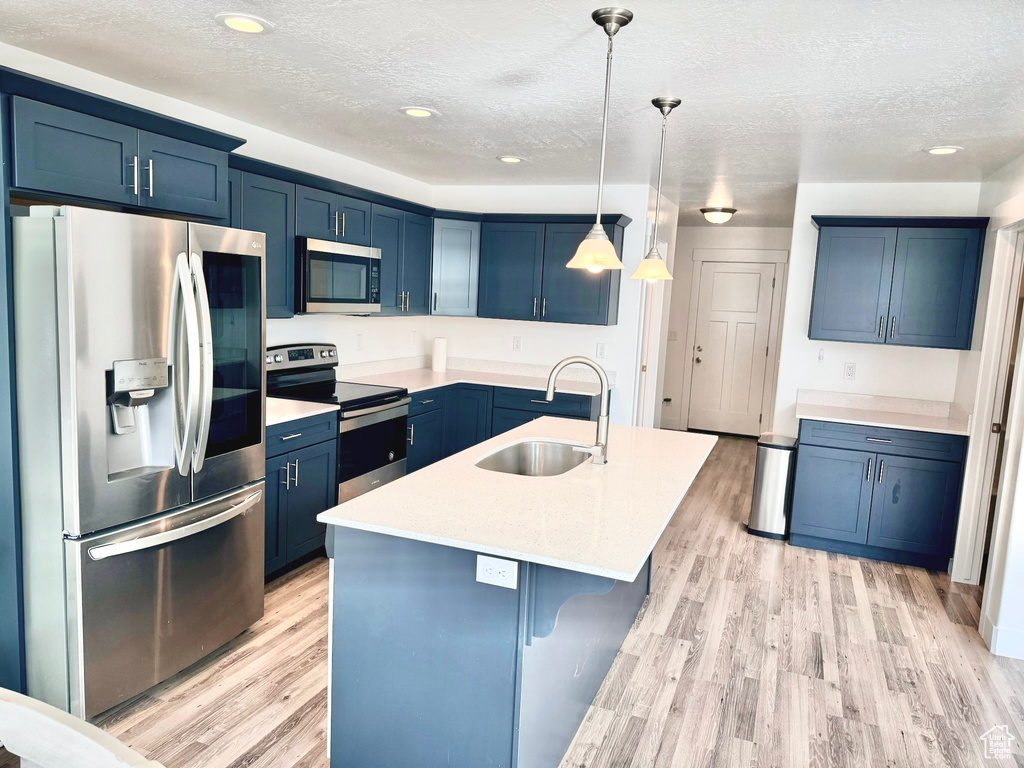 Kitchen featuring appliances with stainless steel finishes, light wood-type flooring, sink, and decorative light fixtures