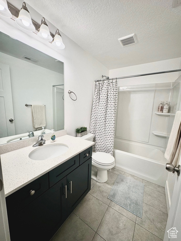 Full bathroom featuring vanity, a textured ceiling, shower / bath combo, tile patterned flooring, and toilet