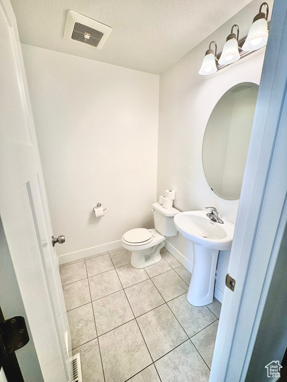 Bathroom featuring a textured ceiling, toilet, and tile patterned floors